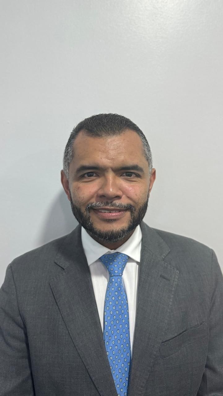 Un hombre con traje y corbata sonríe a la cámara.