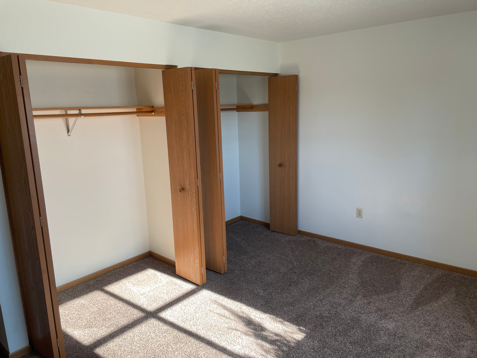 An empty bedroom with a lot of closets and a window.