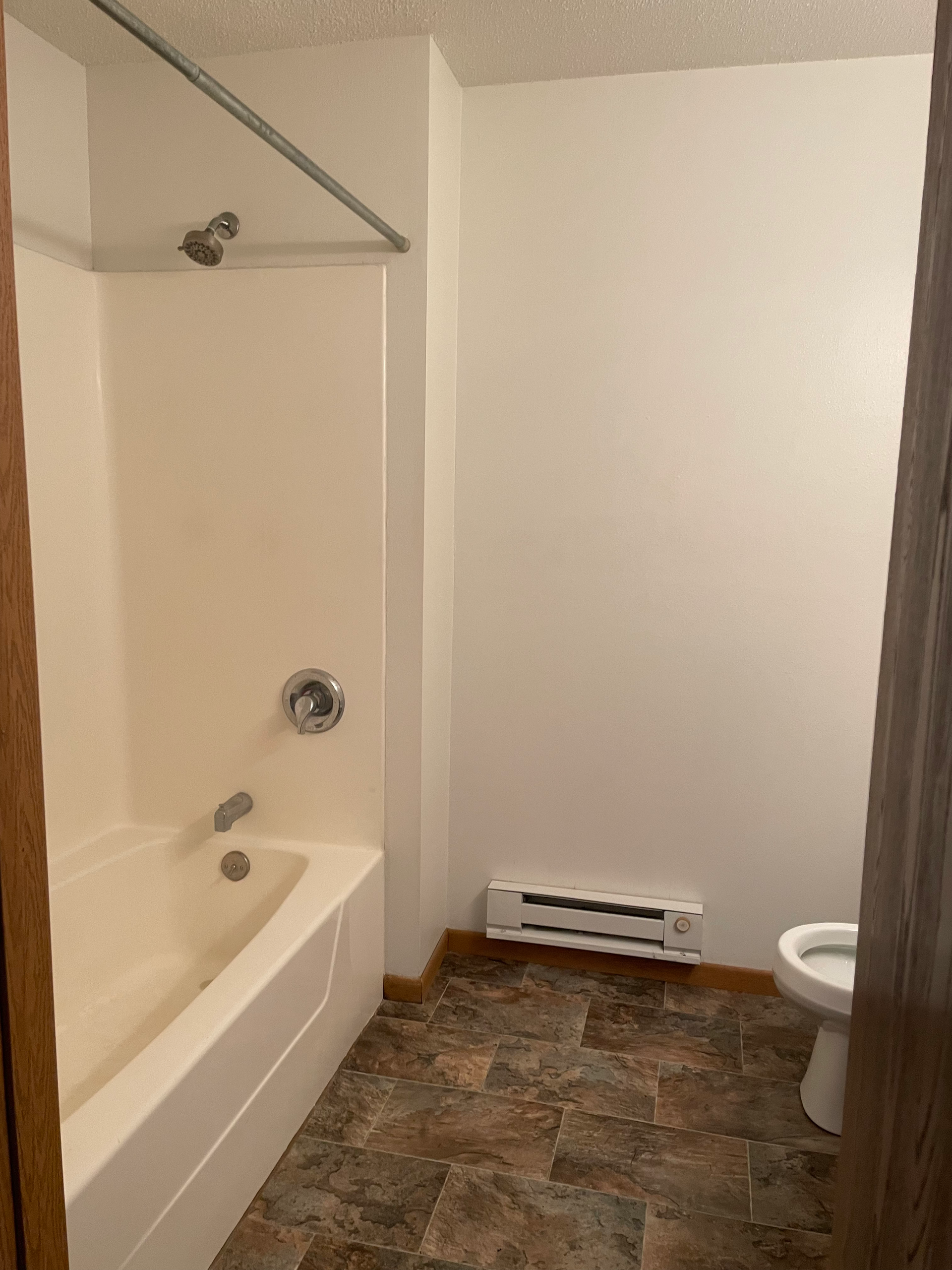 A bathroom with a tub , toilet and shower.