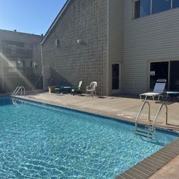 There is a large swimming pool in front of a house.