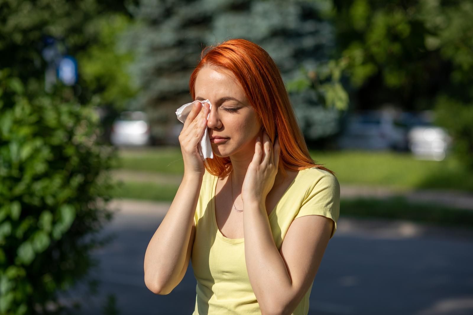 A woman with red hair is covering her face with a napkin.