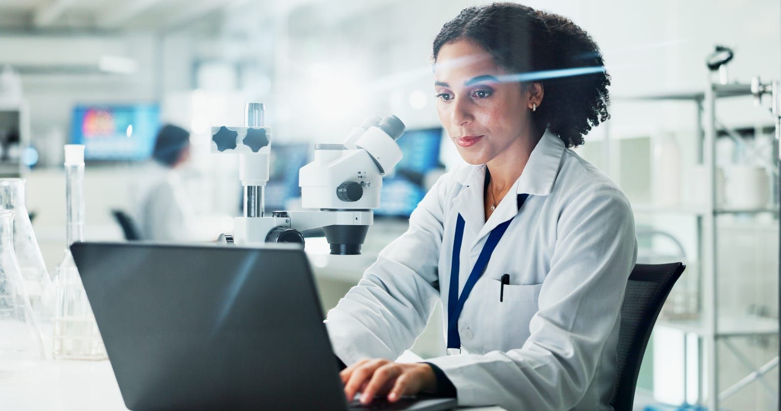 A female scientist is using a laptop computer in a lab.