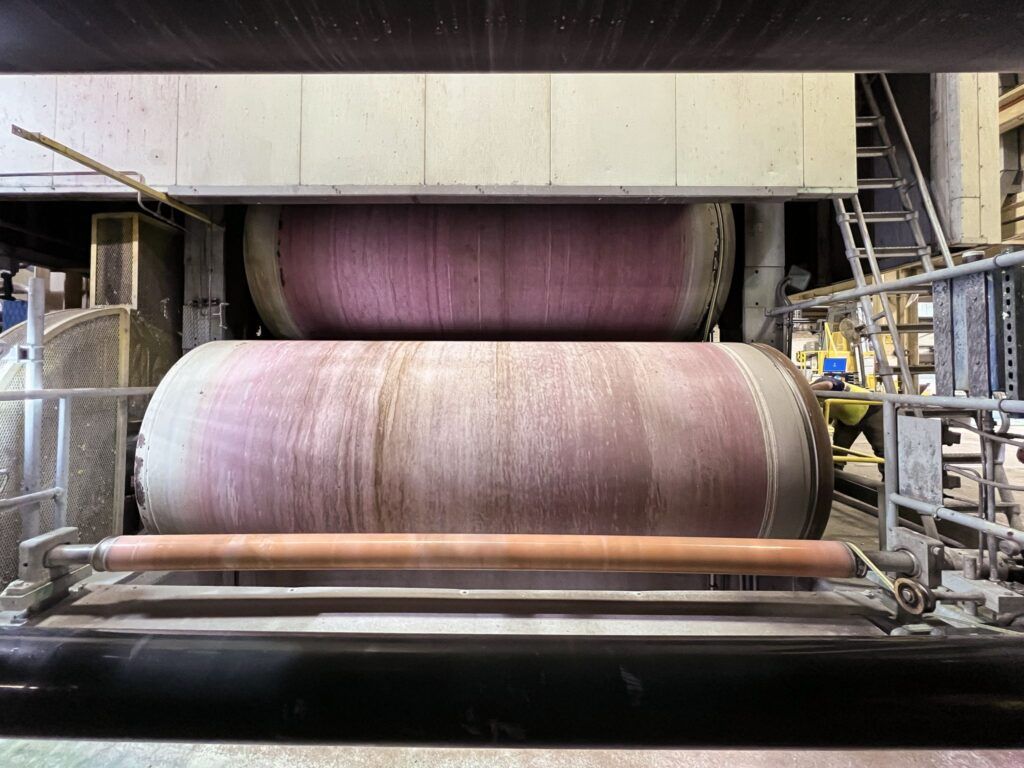 Large industrial rollers in a factory, likely for processing paper or fabric.