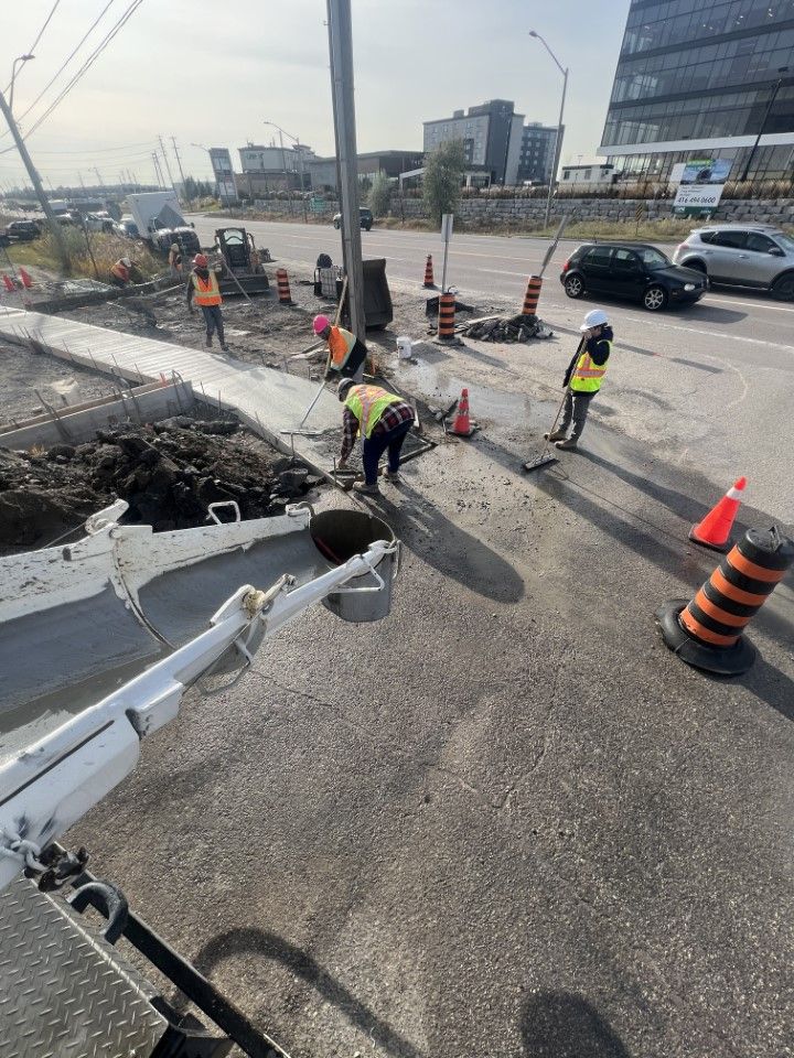 A group of construction workers are working on the side of a road.