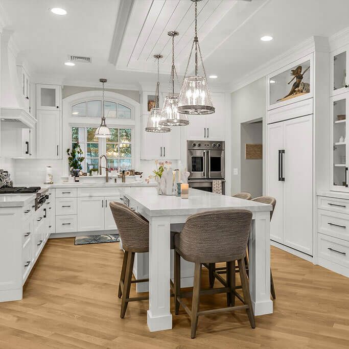 Bright white kitchen with island, pendant lights, and wood floors