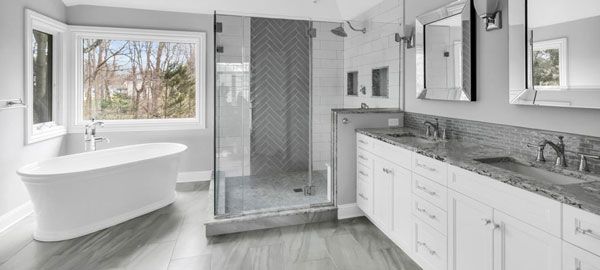 Bright modern bathroom with freestanding tub, glass shower, marble vanity, and large window view