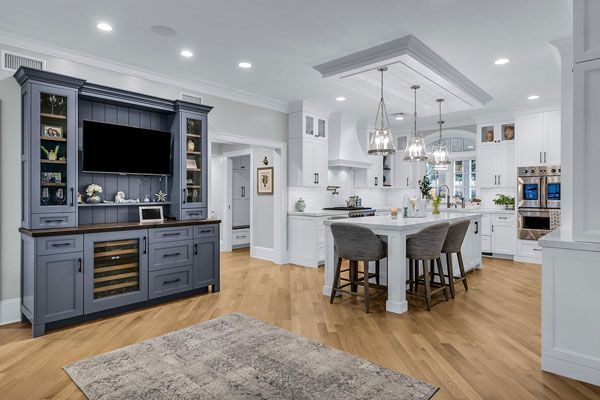 Bright modern kitchen and dining area with blue cabinetry, white island, and hardwood floors