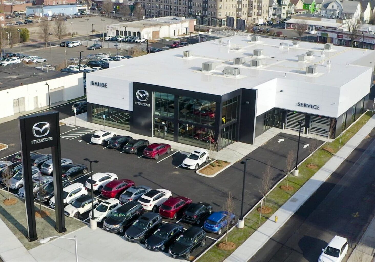 An aerial view of a mazda dealership with a lot of cars parked in front of it.