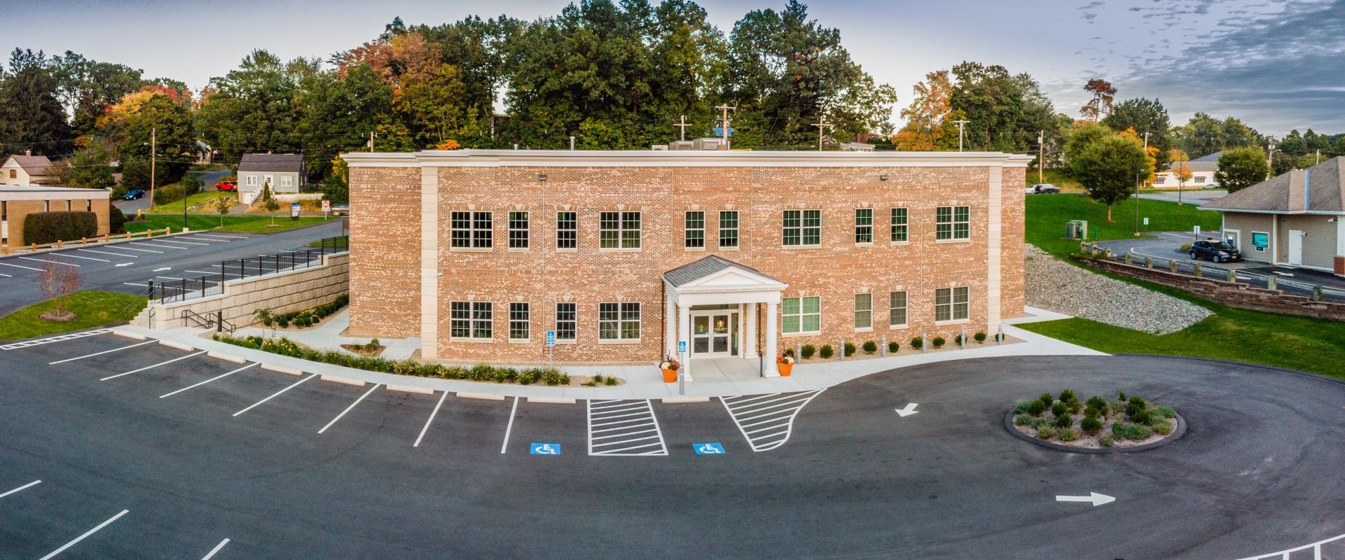 An aerial view of a large brick building with a parking lot in front of it.