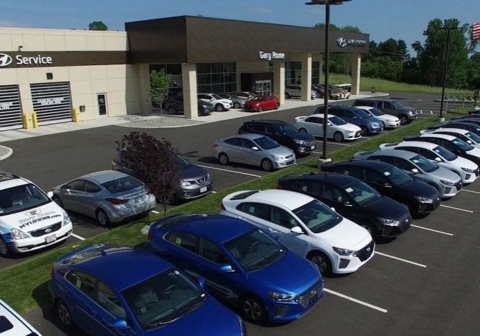 A lot of cars are parked in front of a car dealership