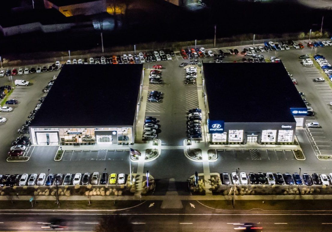 An aerial view of two buildings and a parking lot at night.