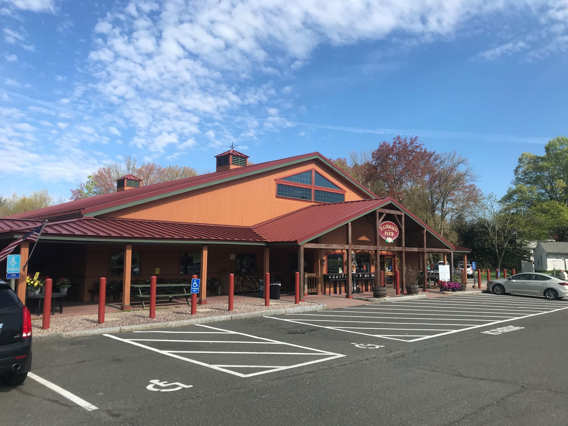 A large building with a red roof and a parking lot in front of it.