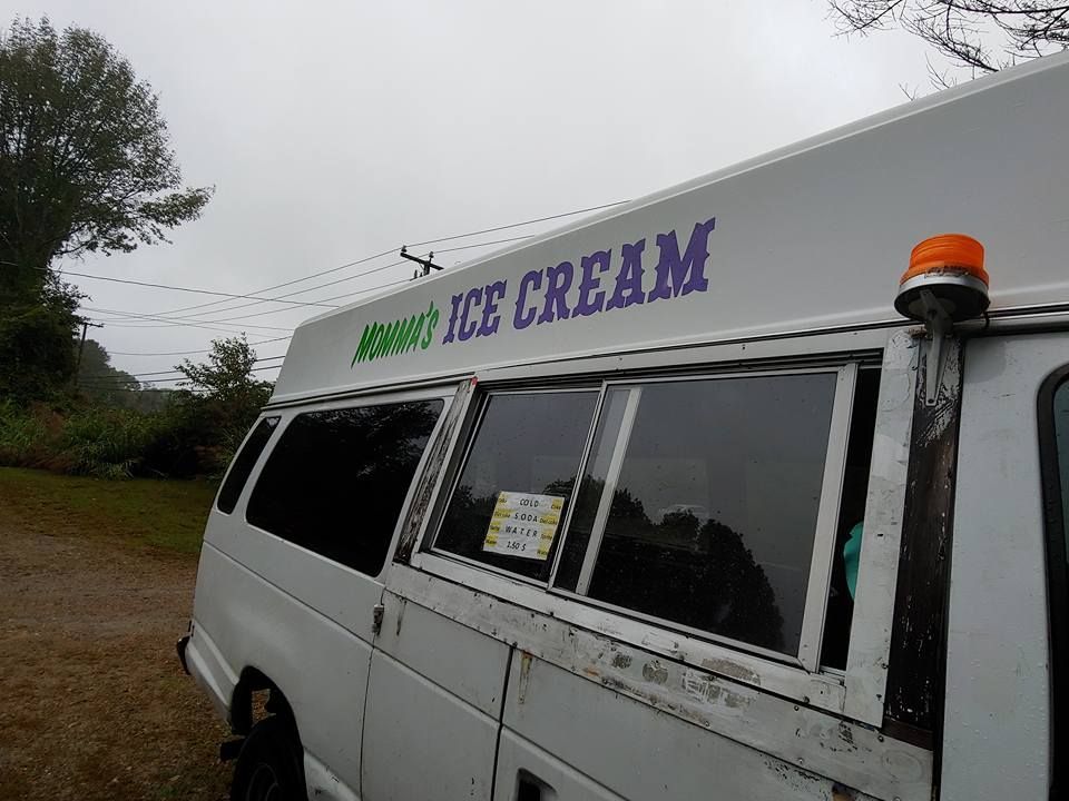 A white ice cream van parked outdoors with purple