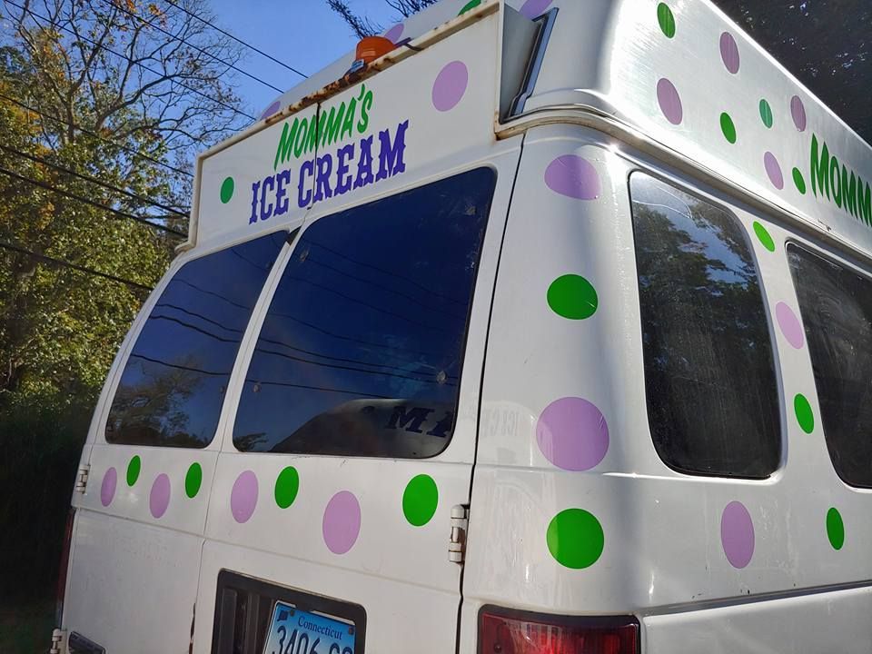 Rear view of a white ice cream van decorated with green and purple polka dots, with