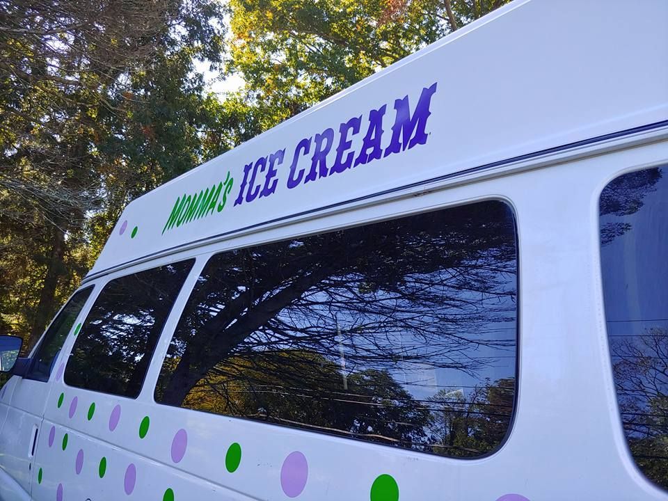 A side view of a white ice cream van decorated with green and purple polka dots, with
