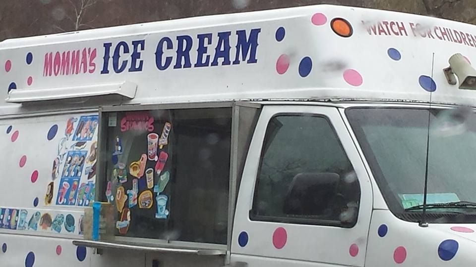 A white ice cream truck with blue and pink polka dots and