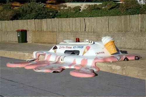 A surreal art installation of a life-sized ice cream van melted into a pink, creamy puddle on a concrete sidewalk.