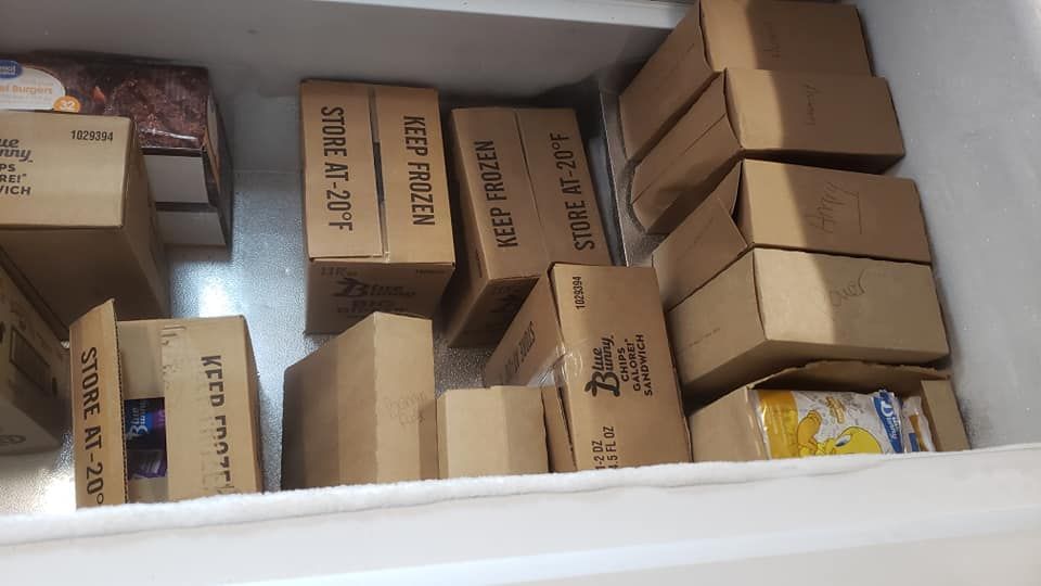 Top-down view of a chest freezer filled with several brown cardboard boxes arranged in organized rows.