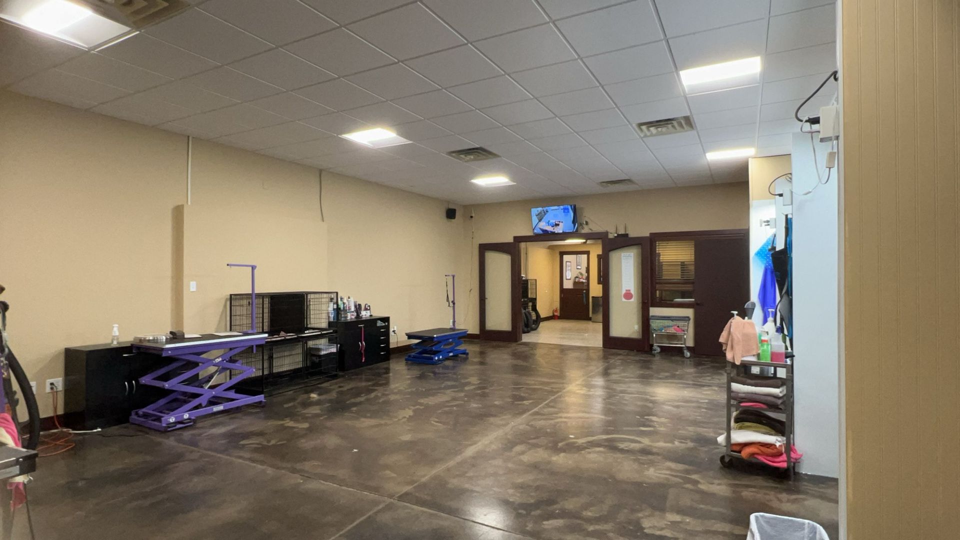 A large room with a concrete floor and a television on the ceiling.