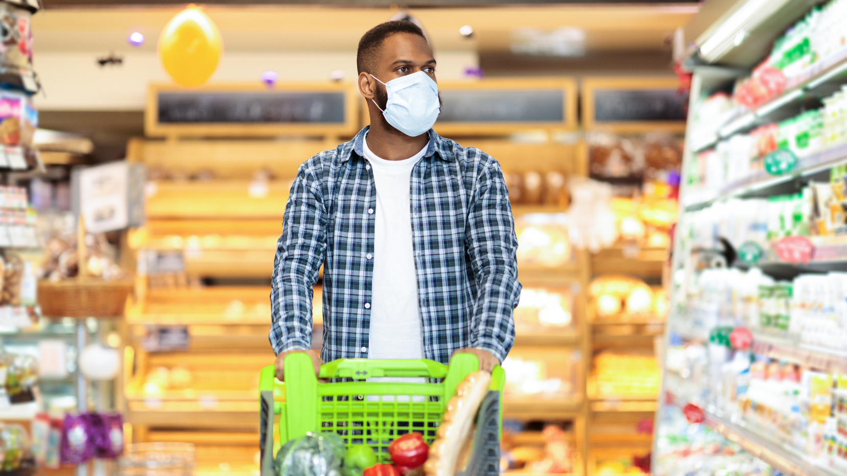A Man Wearing a Mask While in a Grocery Store