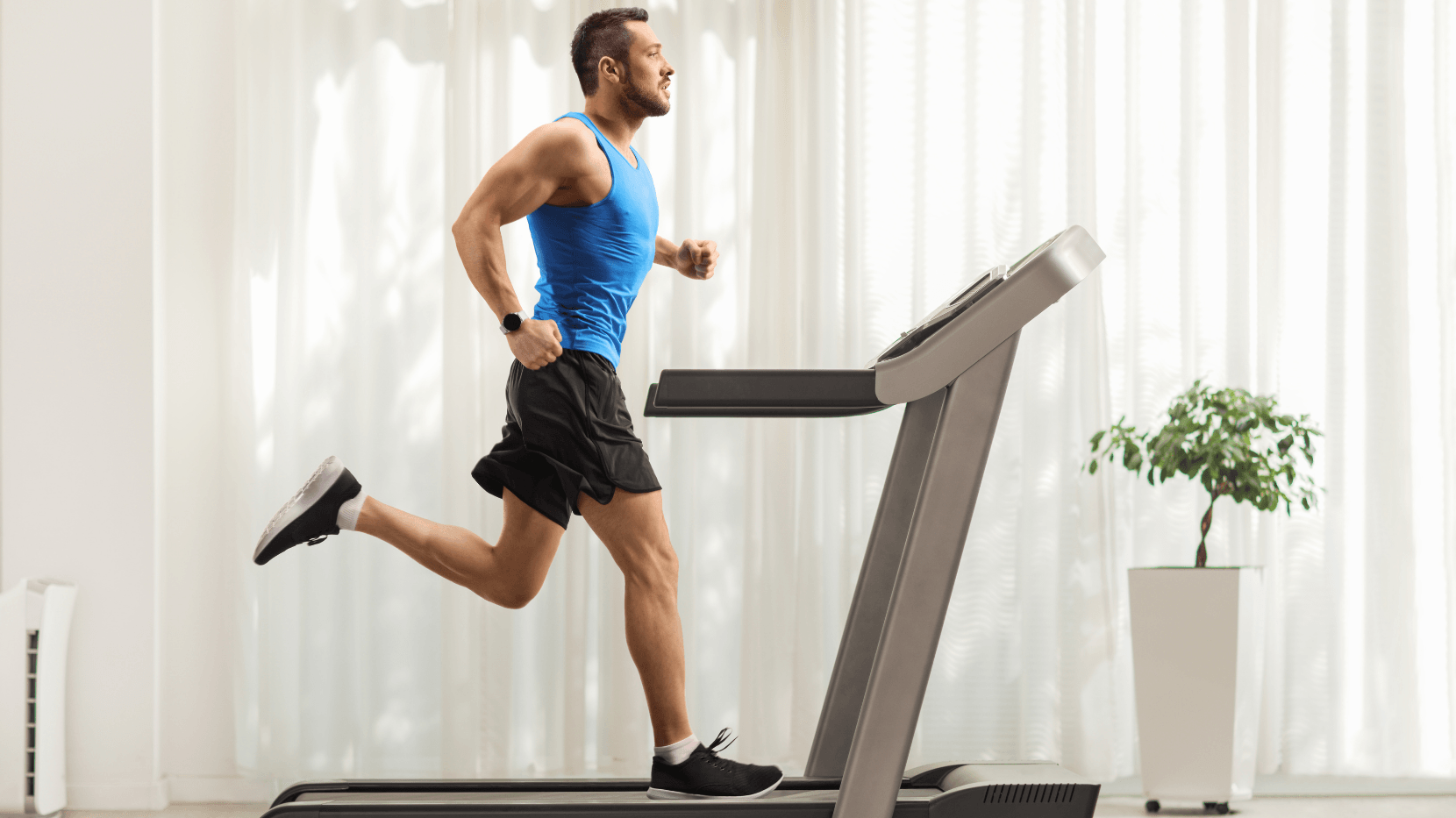 A Man Exercising at Home by Running on a Treadmill