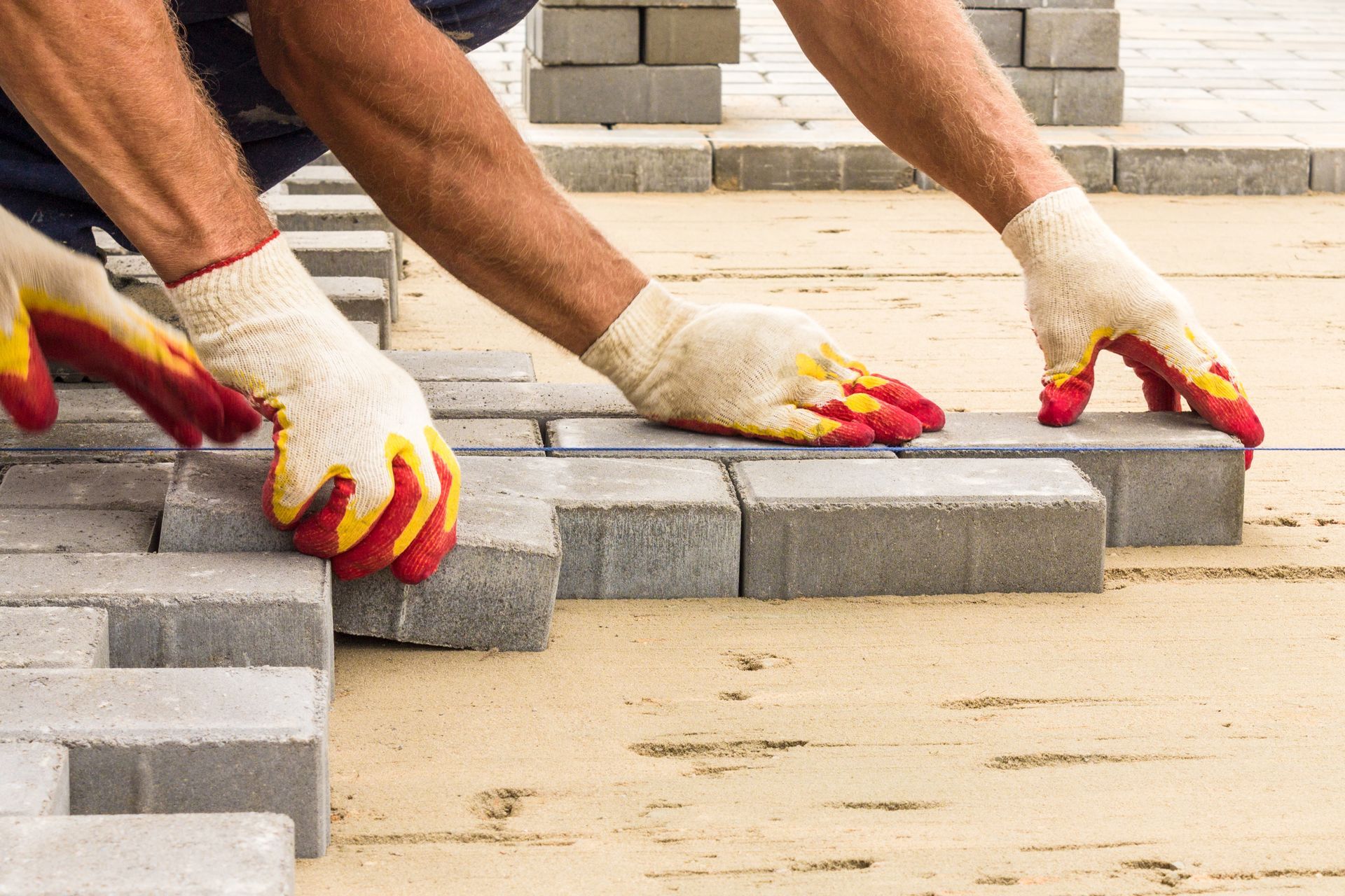 Workers expertly laying paving tiles for brick paver walkway construction in Monmouth County, NJ, enhancing outdoor spaces.