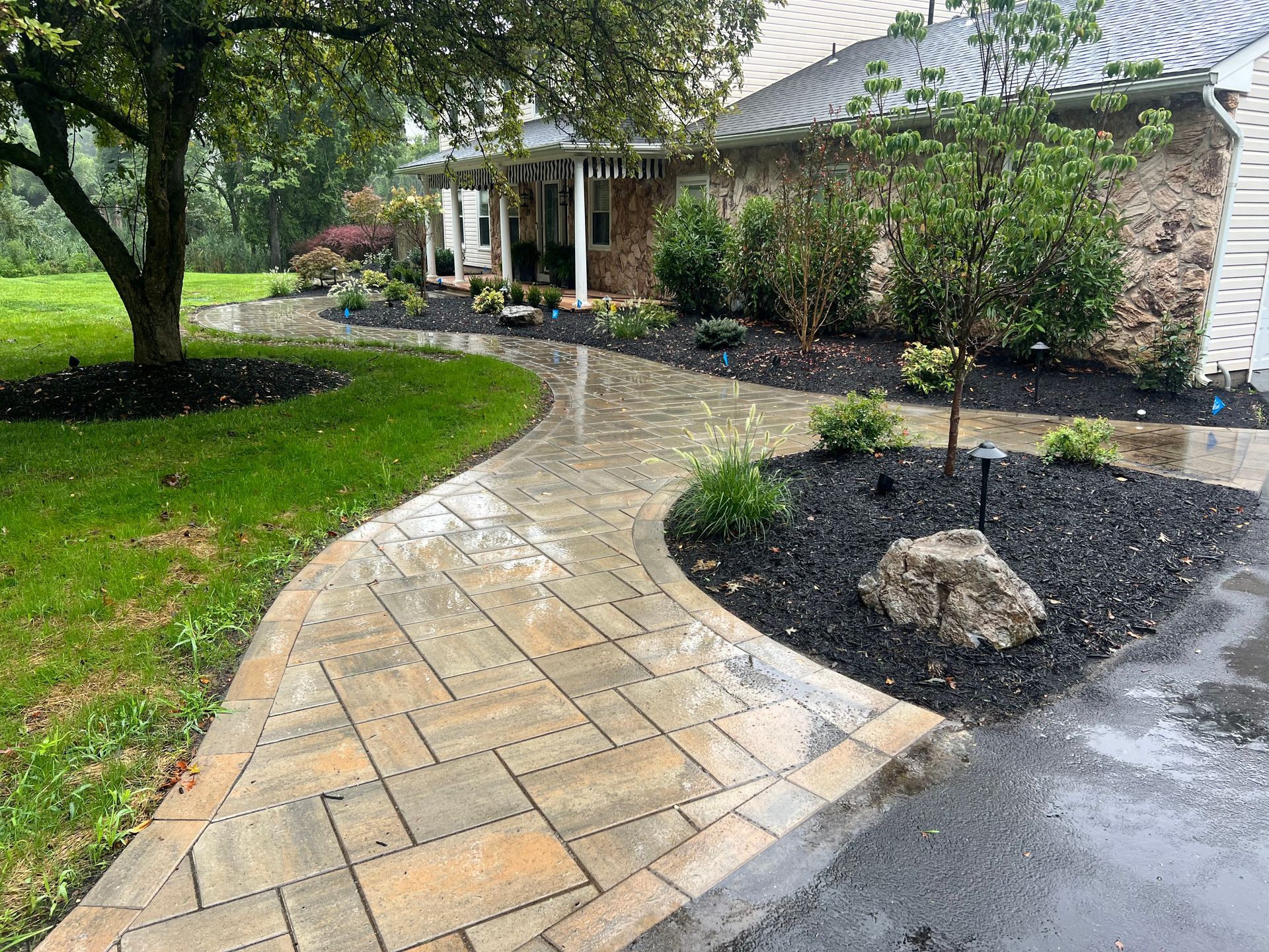 A walkway leading to a house with a tree in the middle of it.