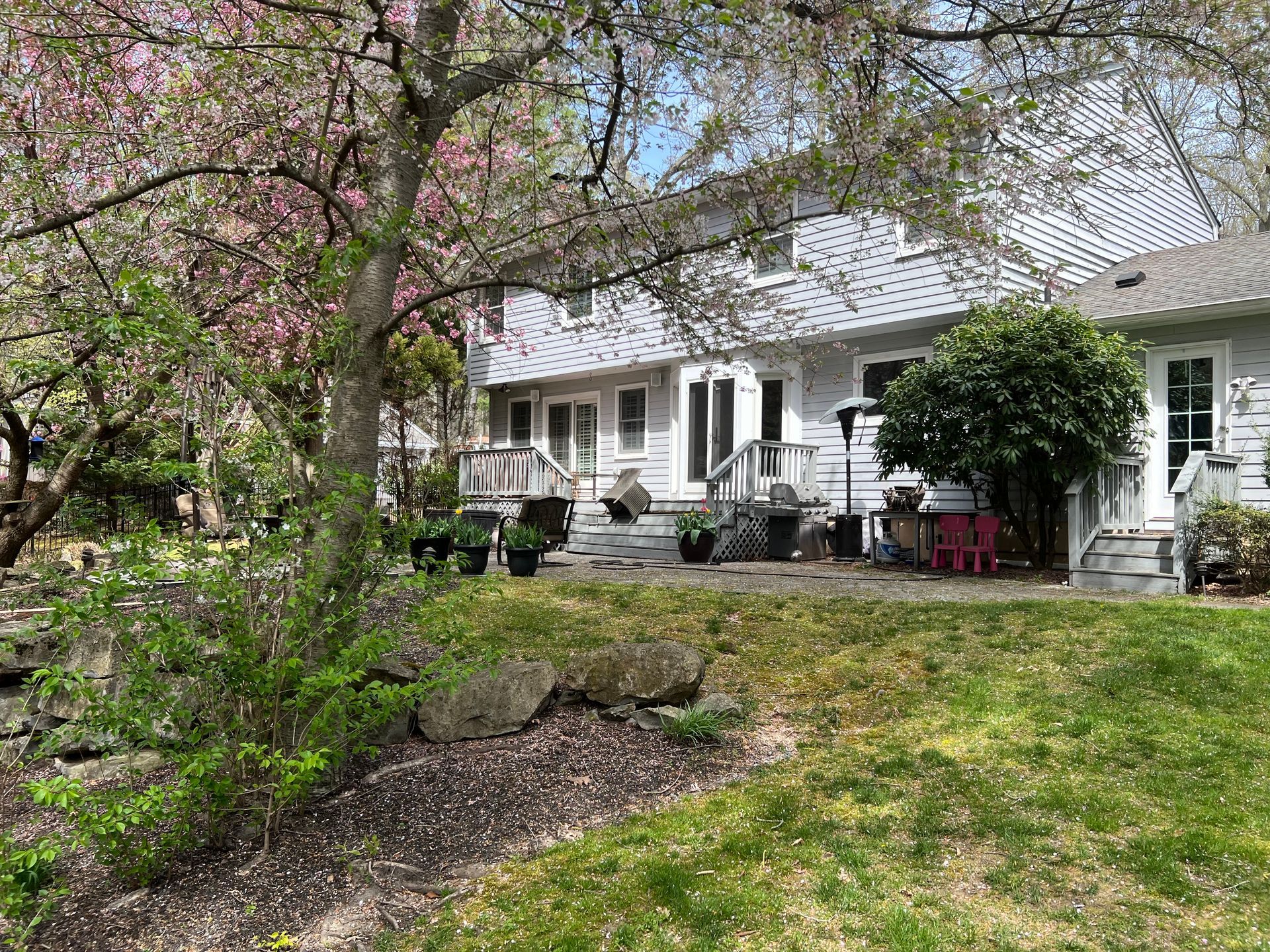 A white house with a lush green yard and trees in front of it