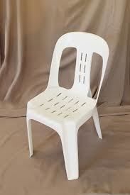 White plastic chair on a brown draped background.