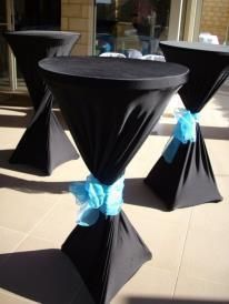Black cocktail tables with blue bows outside.
