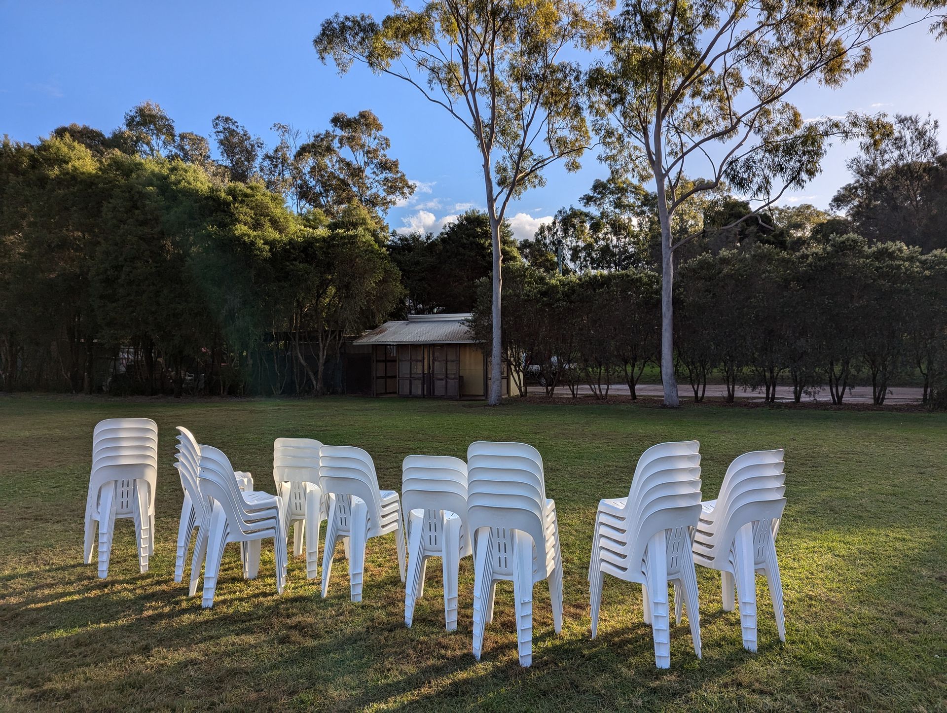 White plastic chairs stacked and in a row outdoors.