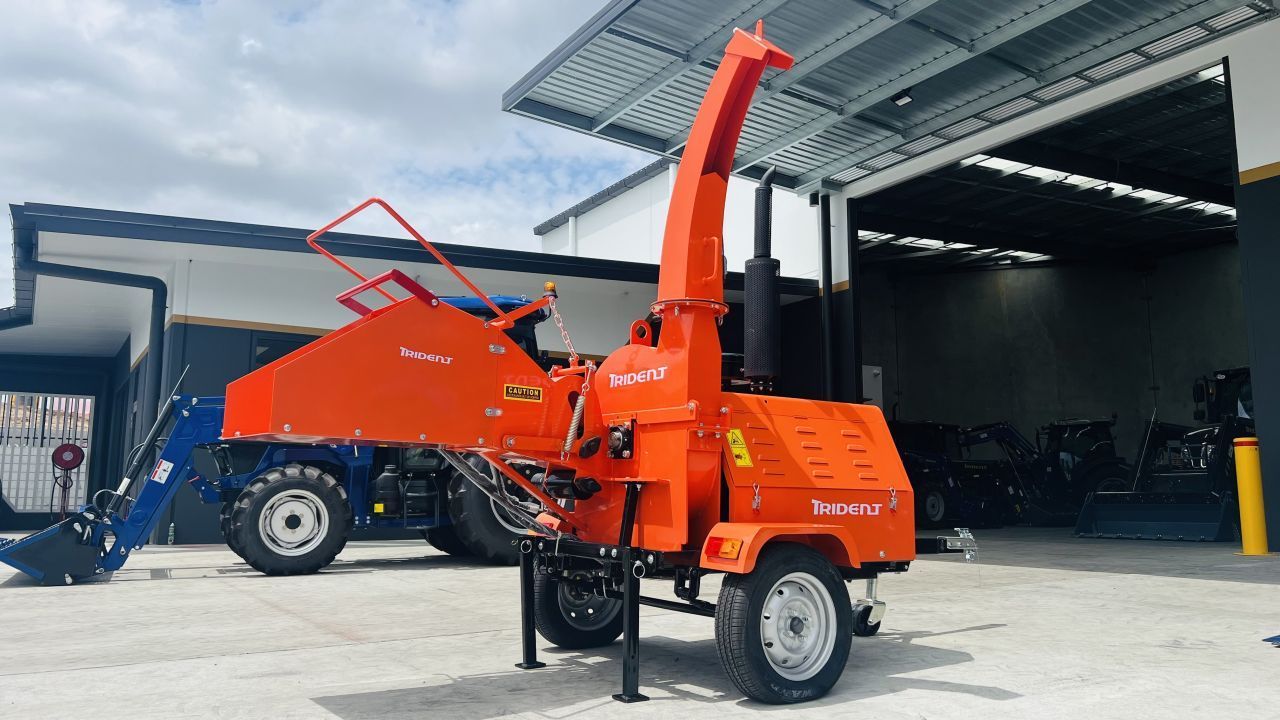 Orange wood chipper machine on wheels, parked outside a building.