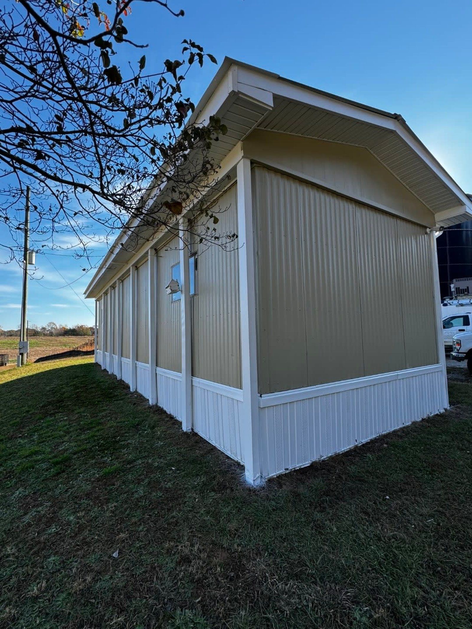 Tan and white prefabricated building on green grass, blue sky.