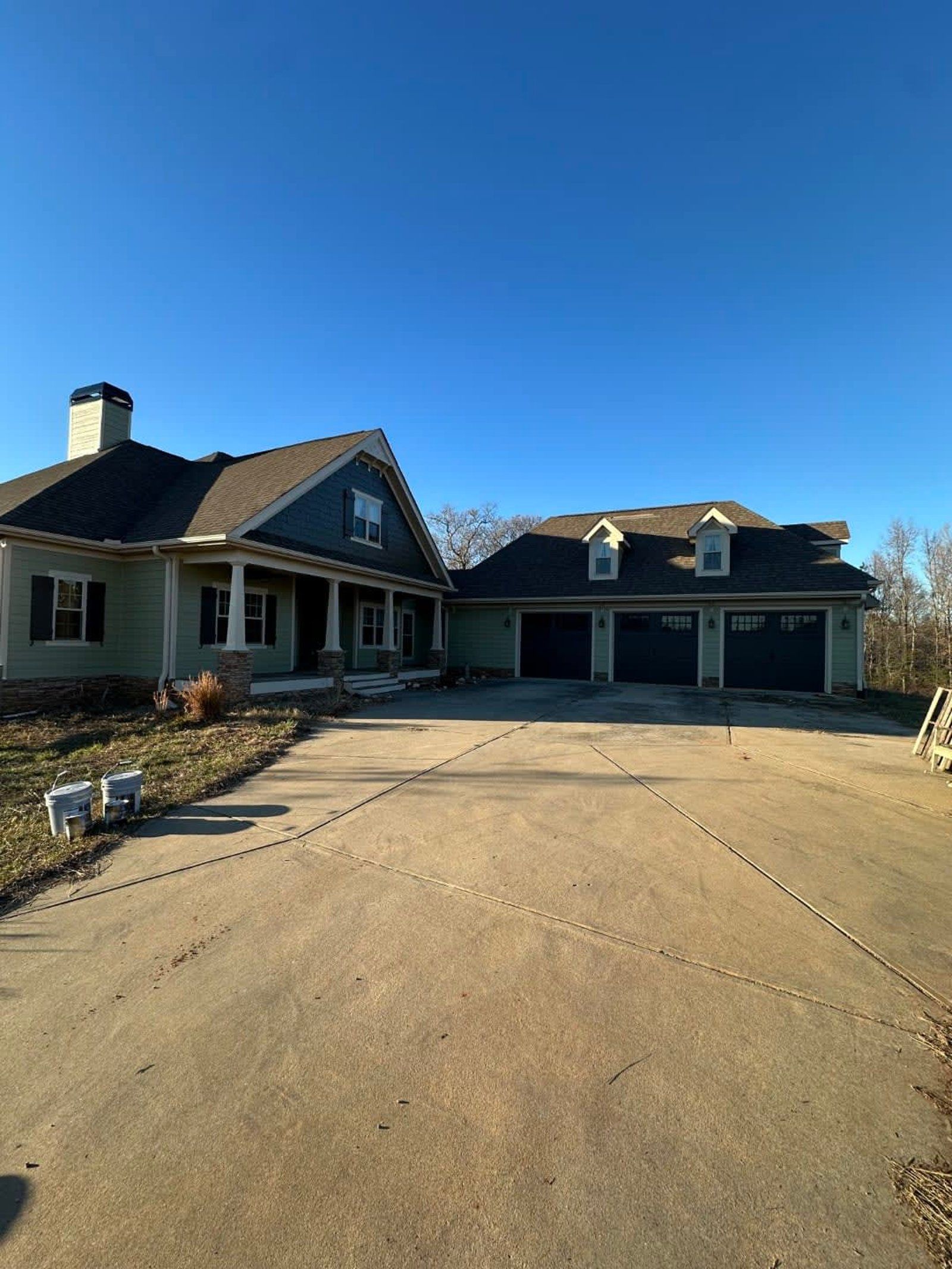 Large house with attached three-car garage, concrete driveway, and blue sky.
