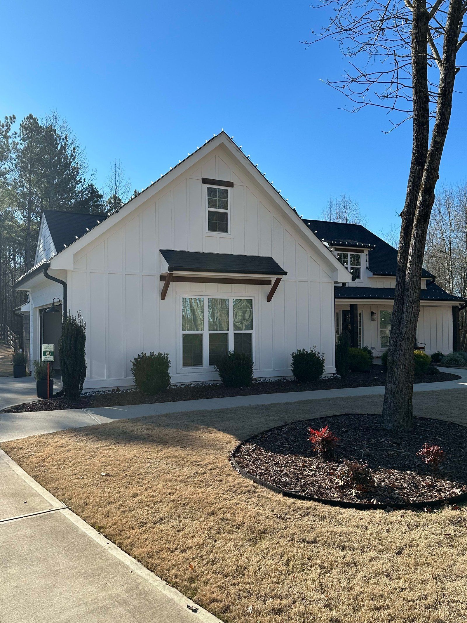 White house with black roof, garage, and front door, on a sunny day.