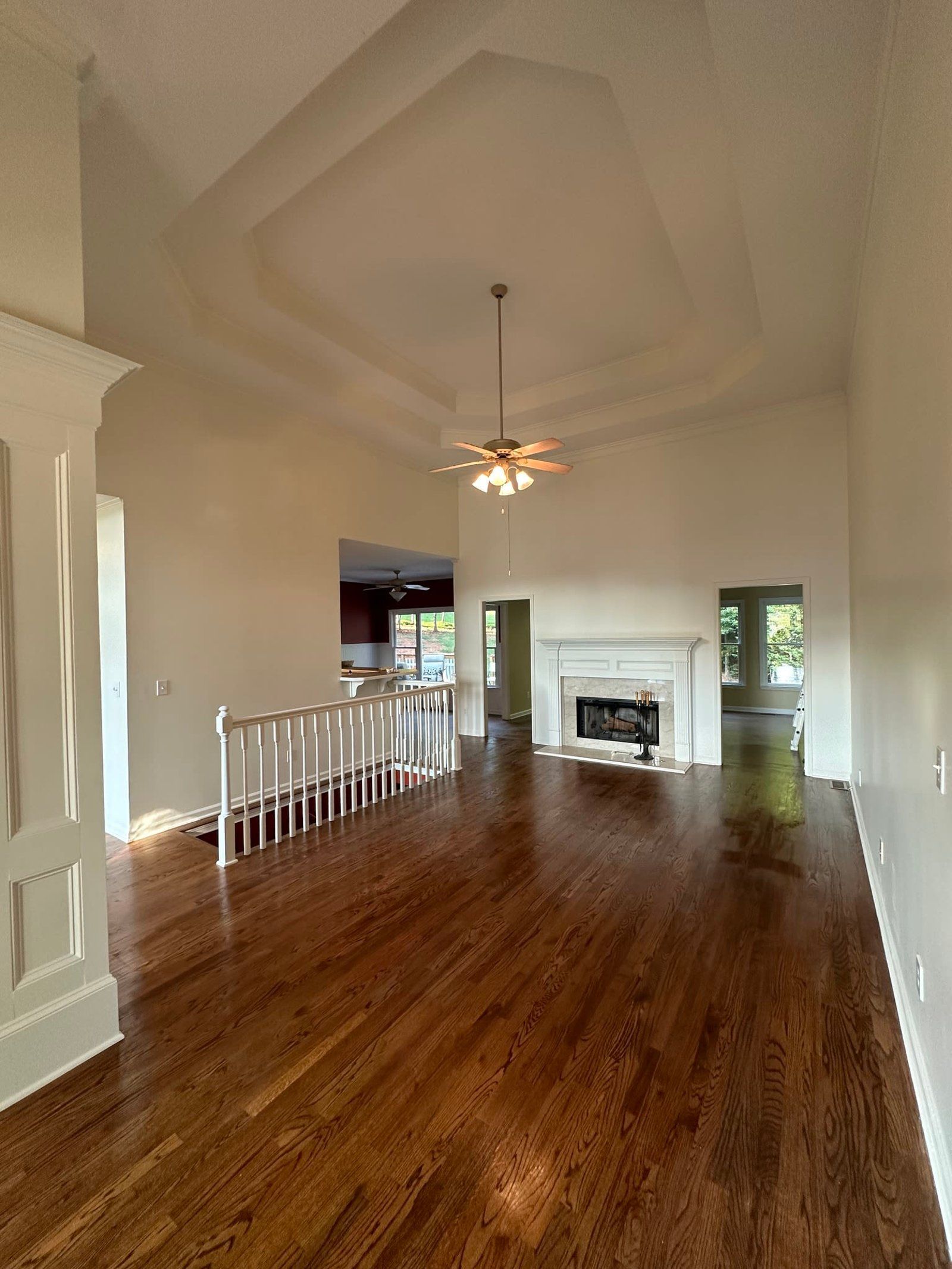 Spacious living room with hardwood floors, fireplace, and tray ceiling.