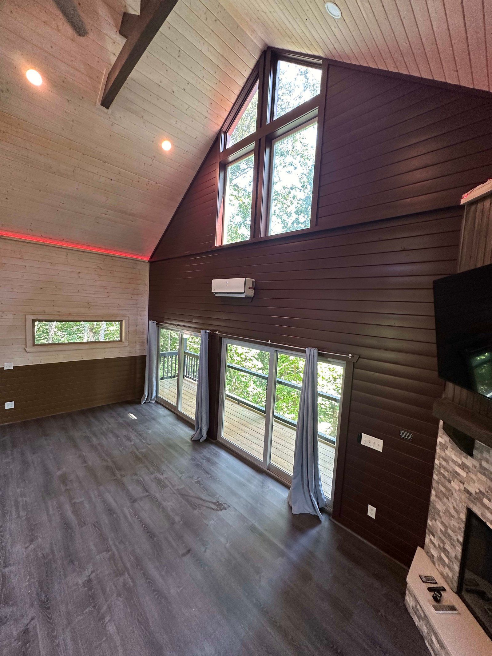 Interior of a room with dark wood paneling, large windows, and a high ceiling.