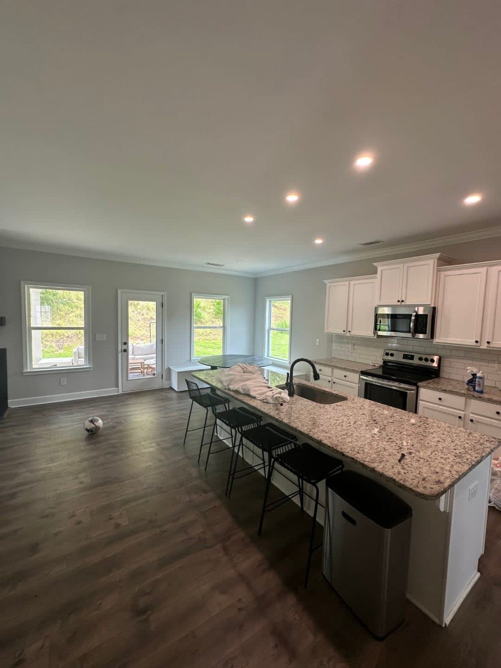 Modern kitchen with a large island, white cabinets, and dark-colored stools.