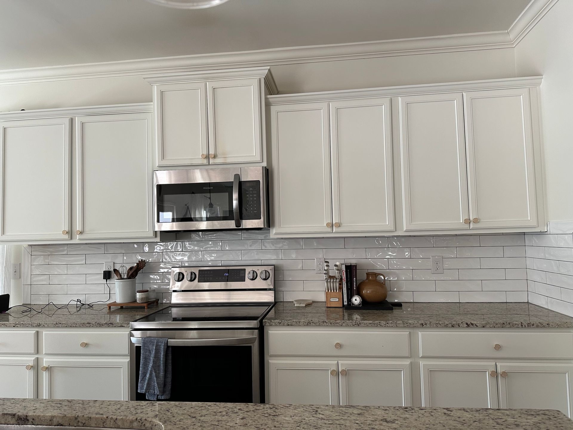 White kitchen cabinets with stainless steel appliances and a white tile backsplash.