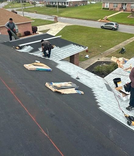 Roofers installing shingles on a residential roof in a suburban neighborhood.