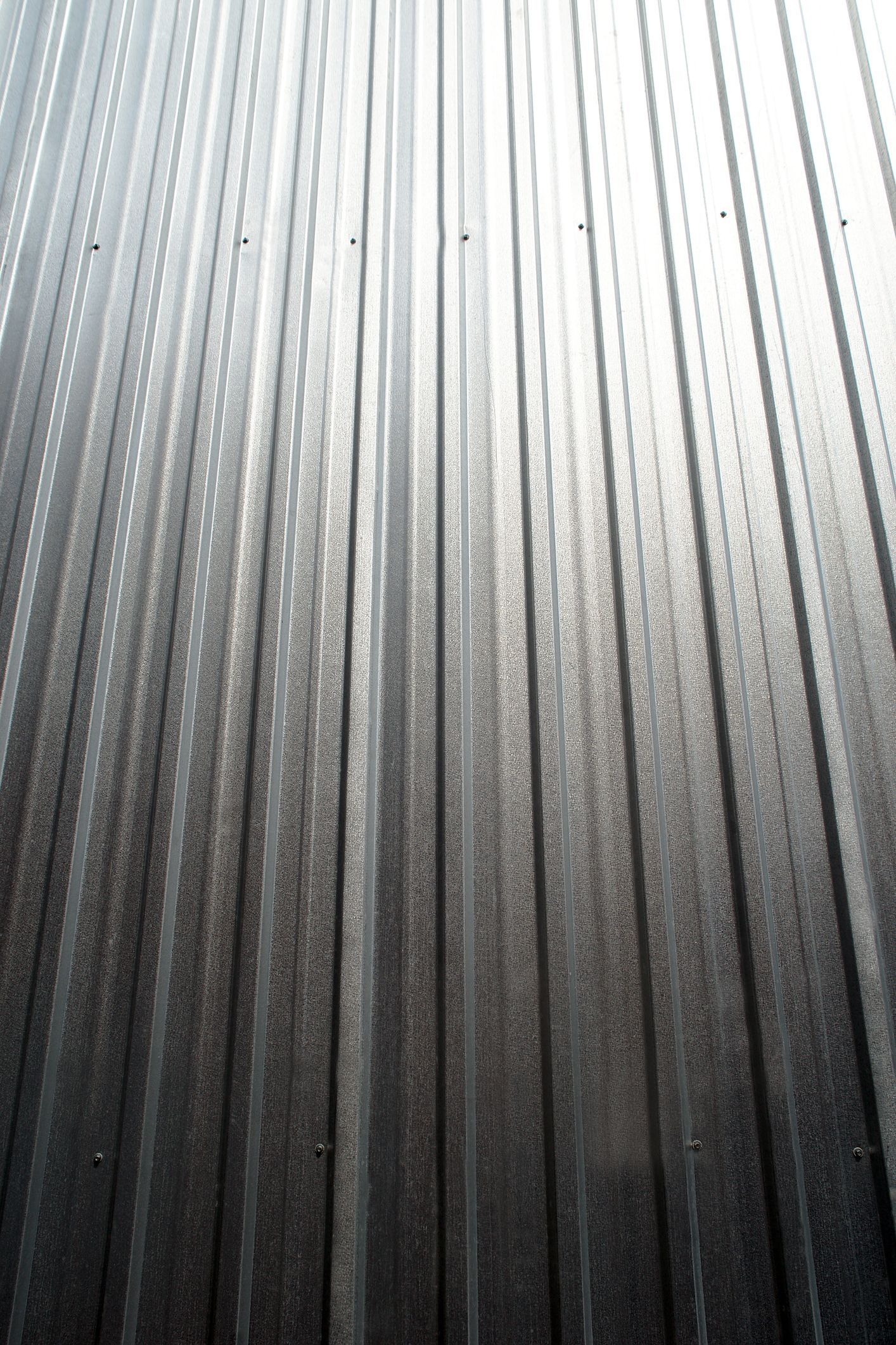 Corrugated metal siding with vertical lines, gradient of gray tones.