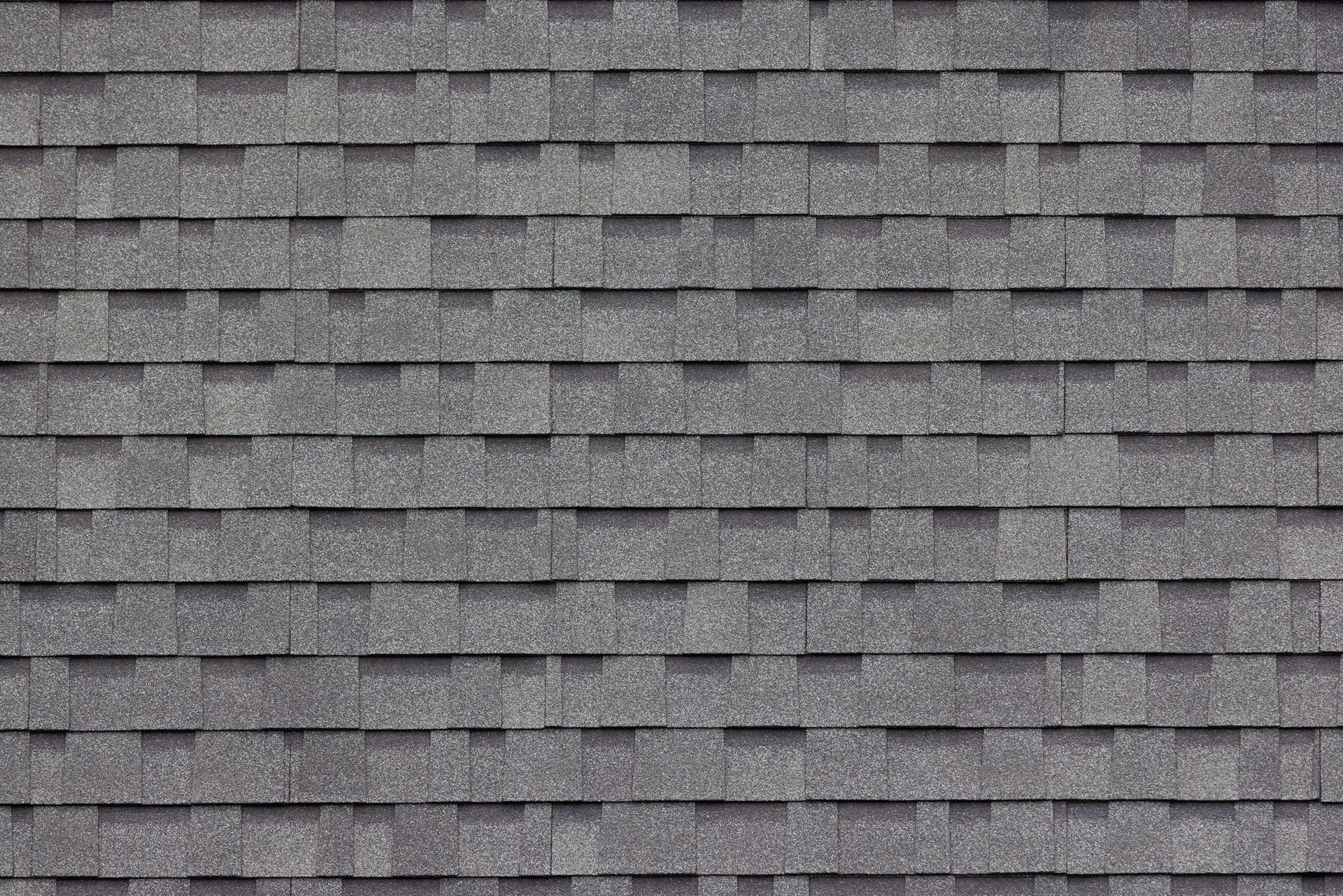 Gray asphalt roof shingles arranged in overlapping rows.