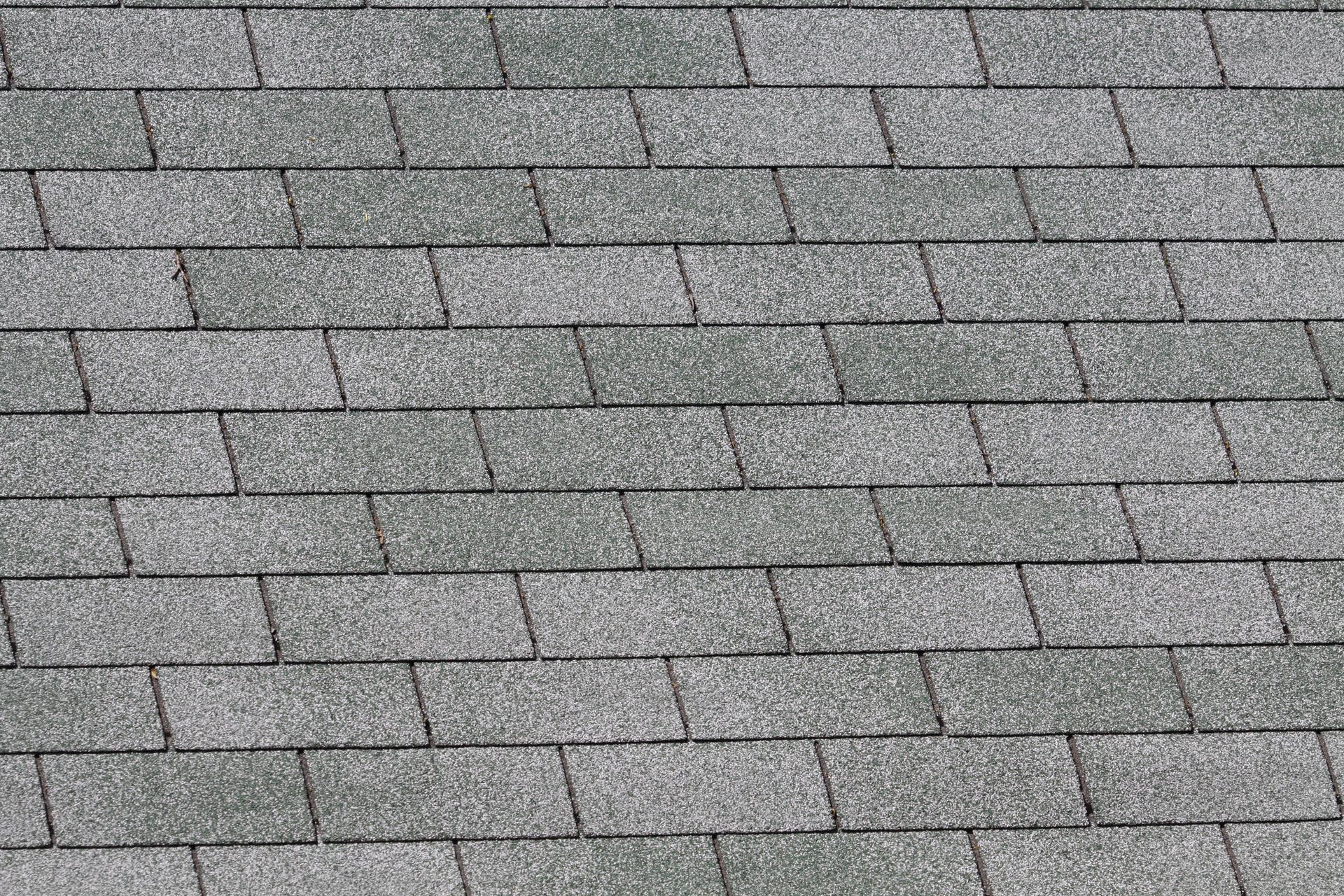 Gray and light green asphalt roof shingles, arranged in a brick-like pattern.