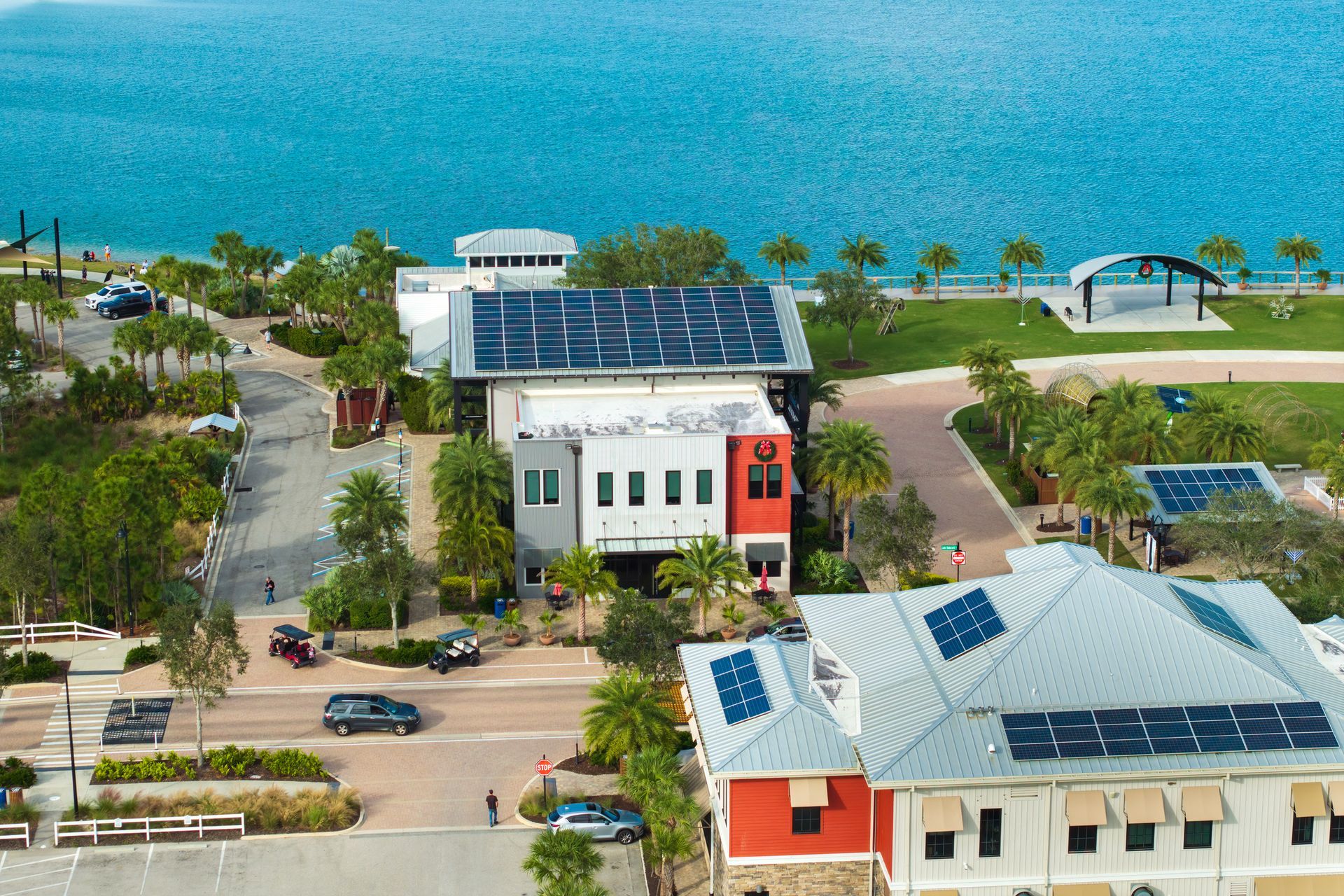 Buildings with solar panels on roofs near a waterfront with a clear blue sky.
