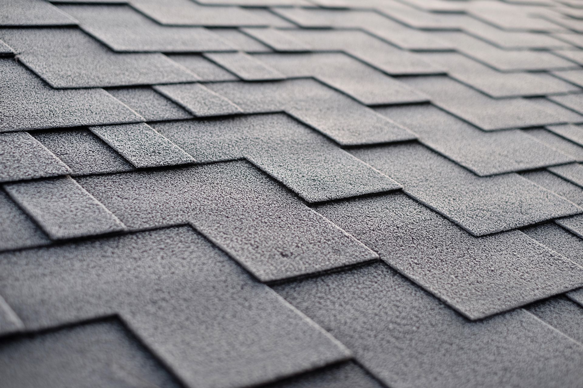 Close-up of asphalt roof shingles, gray in color, with a textured surface.