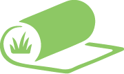 Green roll of turf being unrolled, revealing grass.