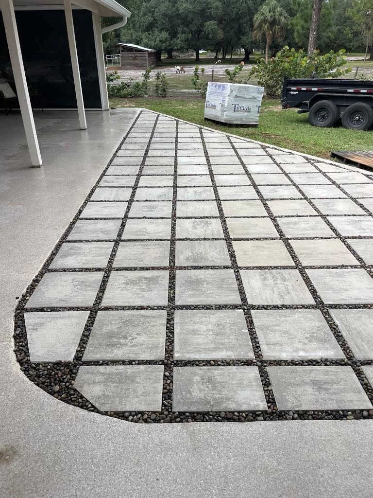 Concrete patio with square pavers separated by dark gravel.
