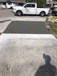 New concrete patch in a driveway, with a white truck in the background.