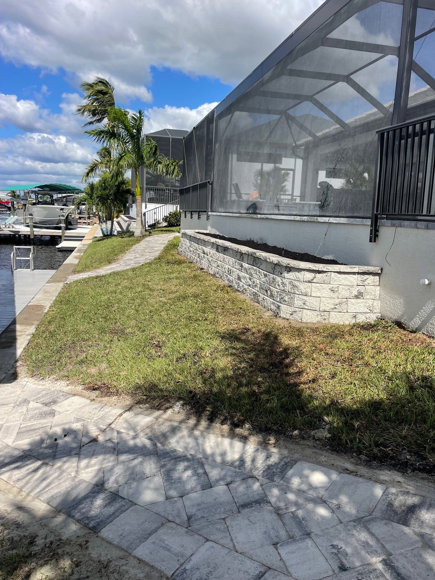 A waterfront patio with a stone wall, overlooking a canal and boats.