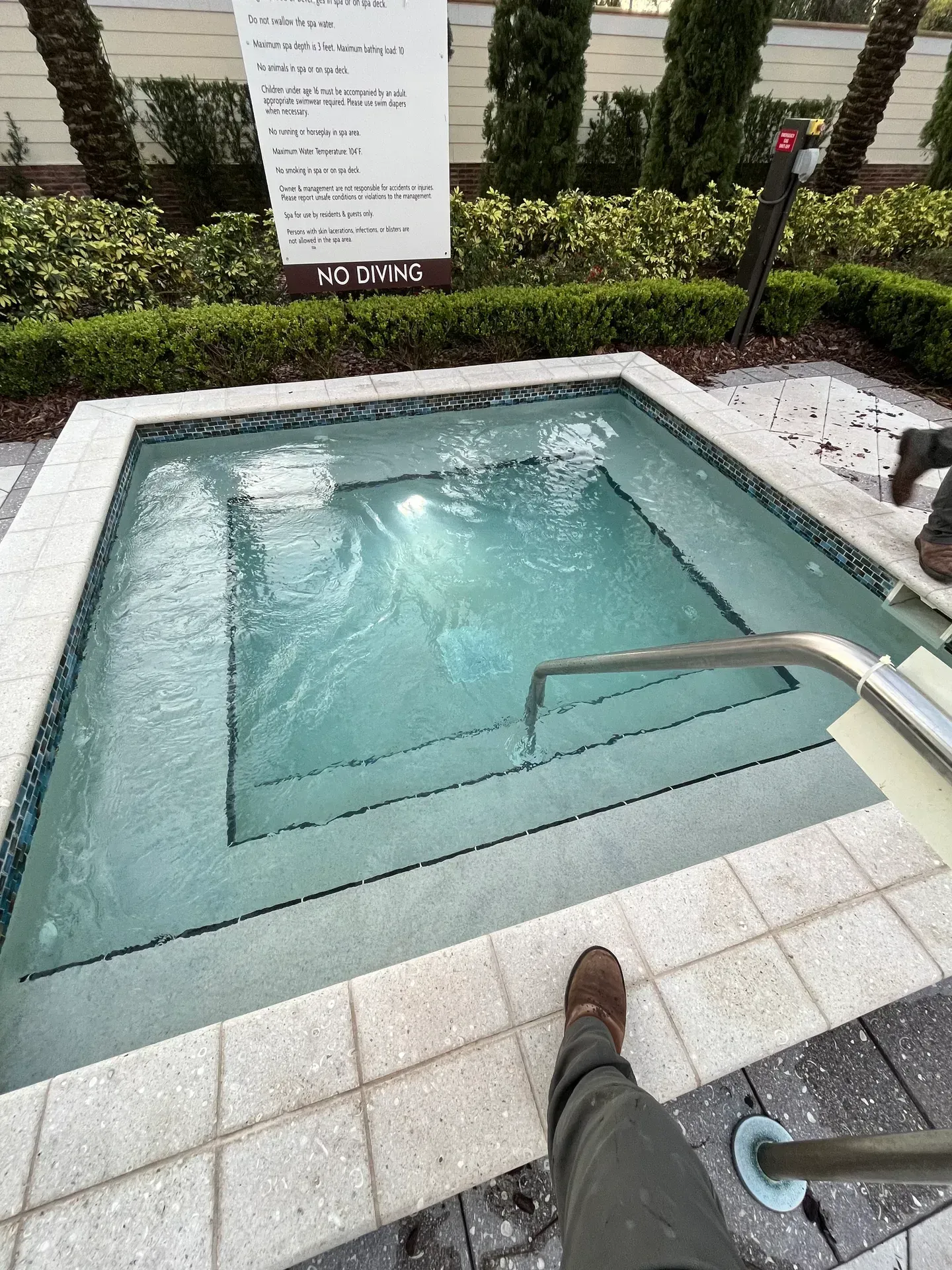 A person is standing in a cleaned hot tub with a sign in the background.